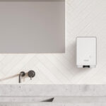 Dispenser elettronico per il sapone lavamani ICON di fianco ad un lavello e a uno specchio